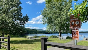 Un parc avec une clôture en bois, des tables de pique-nique et une vue sur un lac.
