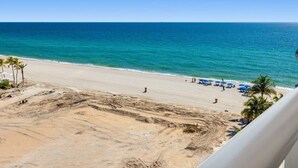 A beach view with a clear sky, sandy beach, and a few people.