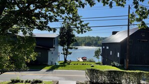 A lakeside property with a dock, a grassy lawn, and two buildings.