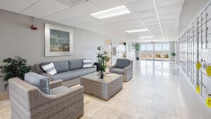 En rummelig lobby med en grå sofa, et sofabord og en potteplante.