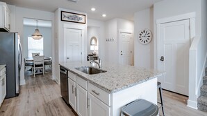 A modern kitchen with white cabinetry, a granite countertop, and stainless steel appliances. - Discover why Serenity is a popular family vacation spot in Perdido Key! (Perdido Key)