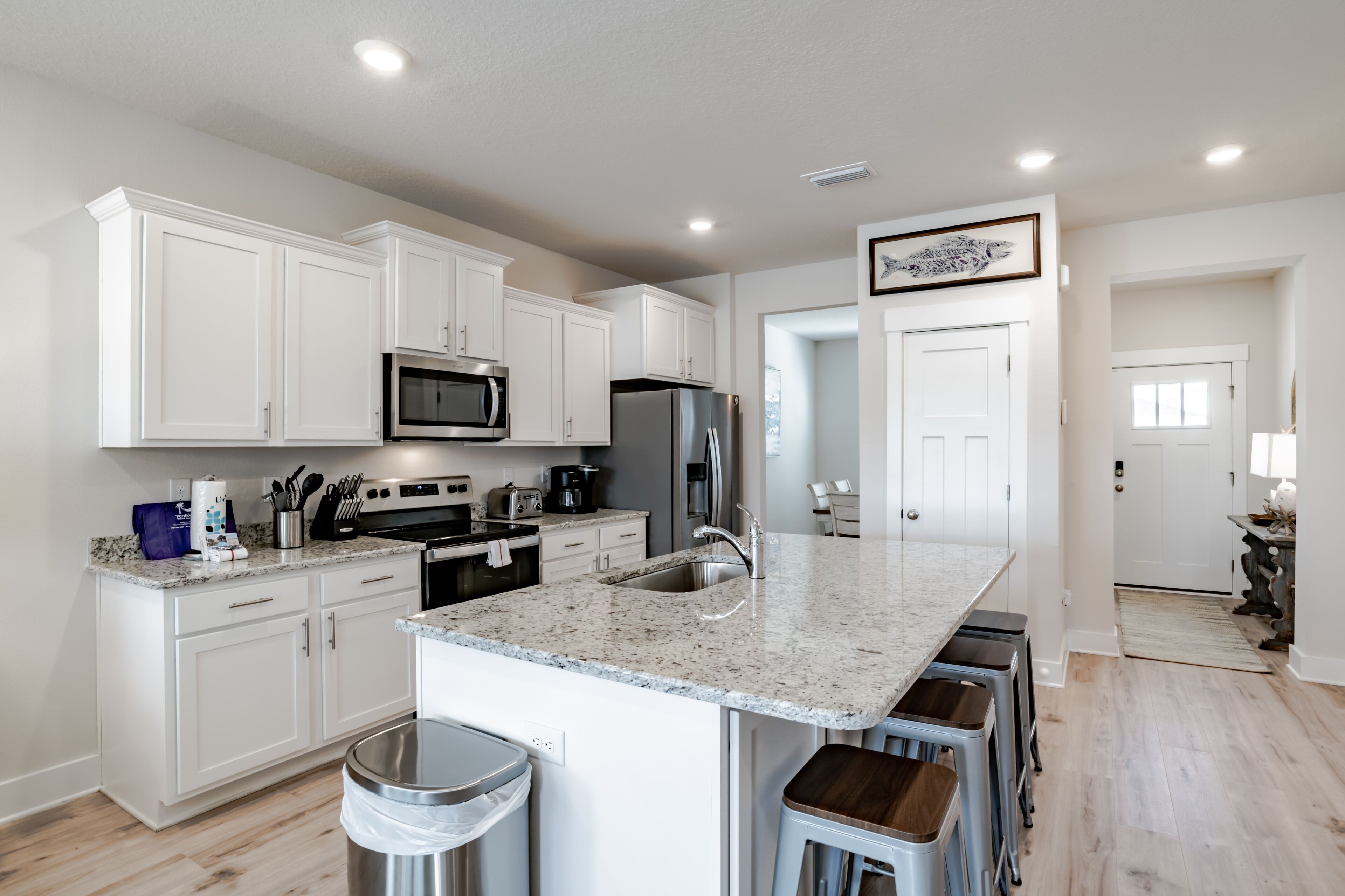 A modern kitchen with white cabinets, stainless steel appliances, and a granite countertop.