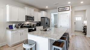 A modern kitchen with white cabinets, stainless steel appliances, and a granite countertop. - Discover why Serenity is a popular family vacation spot in Perdido Key! (Perdido Key)