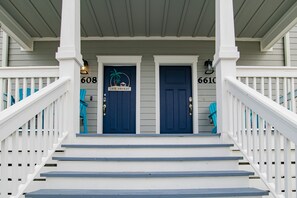 Welcome to Goral Barracks, a charming two-story building with a porch and staircase leading to the entrance.