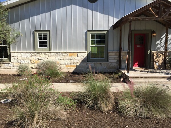Stunning building with a rustic exterior, featuring a prominent red door and beautifully landscaped surroundings.