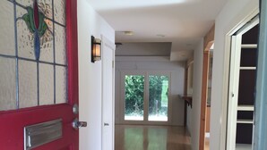 A hallway with a red door, white walls, and a wooden floor. - 5 minutes to downtown! Family home with fenced yard, deck, wooded lot (Austin)