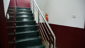 Una escalera con barandales de metal y una pared roja.