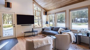 Ein modernes Wohnzimmer mit einem großen Flachbildfernseher, einem grauen Sofa und einem Couchtisch.