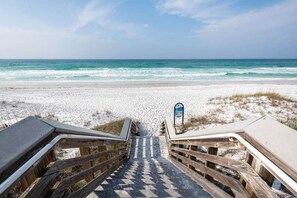 A wooden boardwalk leading to a beach with a signpost.