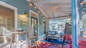 A covered porch with a ceiling fan, wooden chairs, a table, and a blue sofa.