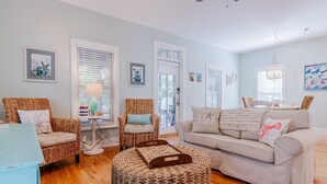 A living room with wicker furniture, a beige sofa, and a wooden floor.