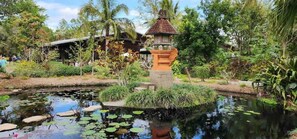 A serene garden with a pond, a small bridge, and a traditional-style gazebo.