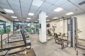 Ein Fitnessstudio mit Laufbändern, Kraftgeräten und einer Spiegelwand.