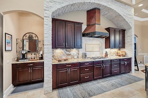 A kitchen with dark wooden cabinets, a stone archway, and a built-in stove.