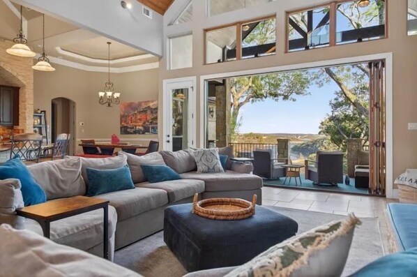 A spacious living area with a large sofa, a coffee table, and a dining area in the background.