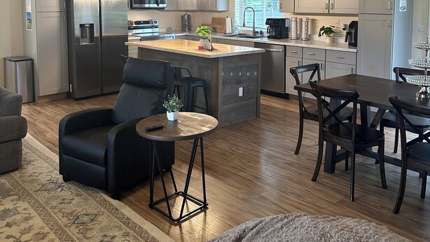 Een moderne keuken met roestvrijstalen apparatuur, een centraal eiland en een eethoek met donker houten meubilair.