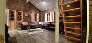 A cozy living room with wooden walls, a sofa, a coffee table, and a ladder.