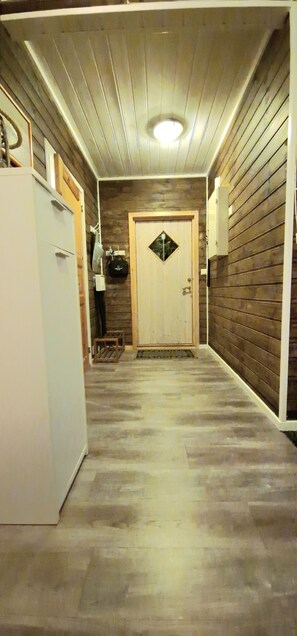 A narrow hallway with wooden walls and a white door at the end.