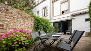 Eine Terrasse im Freien mit Tisch und Stühlen, umgeben von einer Steinmauer und Pflanzen.