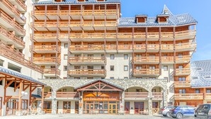 A multi-story hotel with wooden balconies and a stone facade. - Les Balcons du Soleil 4013 (Les Deux Alpes)