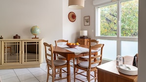 A dining area with a wooden table, chairs, a globe, and a window with a view of trees. - Les Rives de L'Erdre (Nantes)