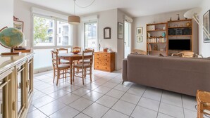 A spacious living room with a dining area, a sofa, and a bookshelf. - Les Rives de L'Erdre (Nantes)