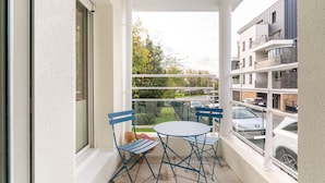 A balcony with a table and chairs, a view of parked cars, and a building in the background. - Les Rives de L'Erdre (Nantes)