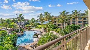 Un resort con piscina rodeada de palmeras y vista al océano.