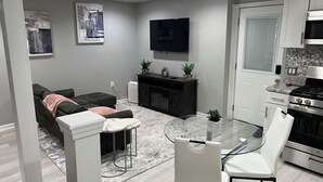 Una sala de estar moderna con un sofá, una mesa de centro de vidrio y un televisor montado en la pared.