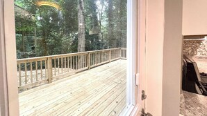 Una terraza de madera con barandilla que da a una zona boscosa.