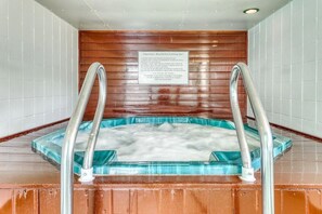 Relax in a serene hot tub surrounded by a wooden wall and glass base.