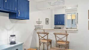 Una cocina con armarios azules, una mesa de comedor de madera y dos sillas de mimbre.