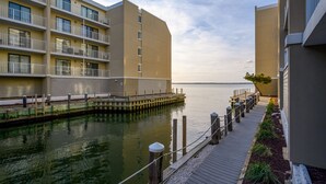 Un hotel frente al agua con una terraza de madera, vista al agua y un edificio con balcones.
