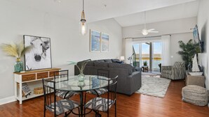 Un salón moderno con una mesa de comedor de cristal, sofá gris y vistas al exterior.