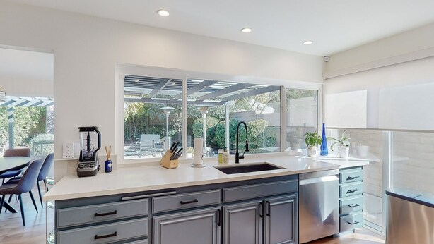 A modern kitchen with a large window, stainless steel appliances, and a built-in dishwasher.