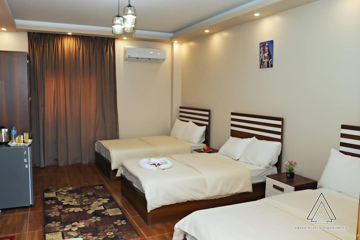Habitación de hotel con dos camas, un escritorio y una mesita con fruteros.