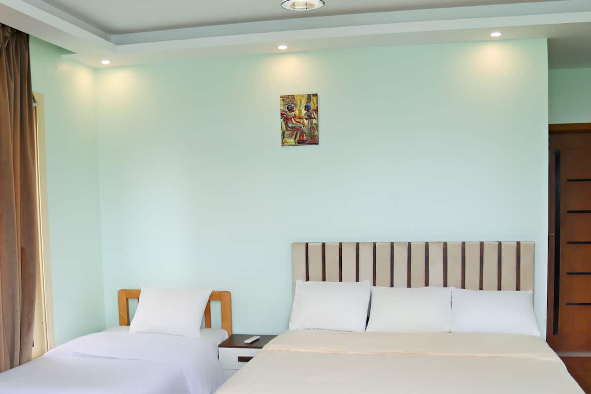 Habitación de hotel con dos camas, un cabecero de madera, una mesita y un cuadro en la pared.