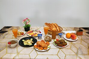 A breakfast table with various dishes, including bread, fruits, and a drink. - Grand Museum Pyramids Inn (Kirdasah)
