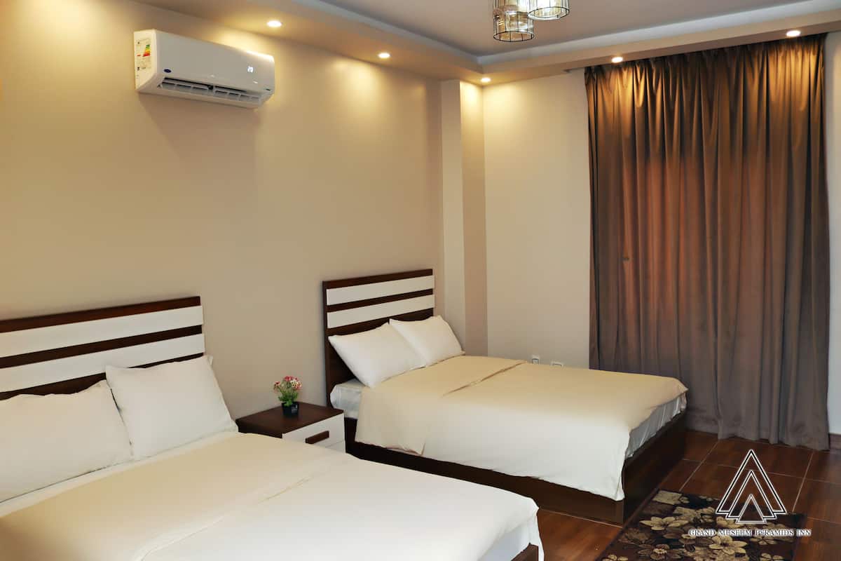 Habitación de hotel con dos camas, aire acondicionado de pared y un ventanal con cortinas.