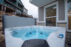 Un jacuzzi con termómetro digital, con un edificio residencial de fondo que tiene balcones y ventanas amplias.