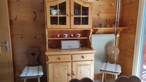 Ein Holzkabinett mit Glastüren, ein kleiner Tisch und zwei stuhlähnliche Sitzgelegenheiten in Herzform.