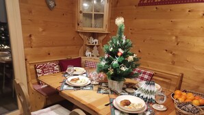 Ein Holztisch für zwei Personen gedeckt mit Essen, Gläsern und einer kleinen Weihnachtstanne.