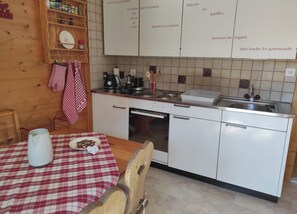 Ett kök med ett träskåp, en kaffebryggare, en vattenkokare och ett handfat.