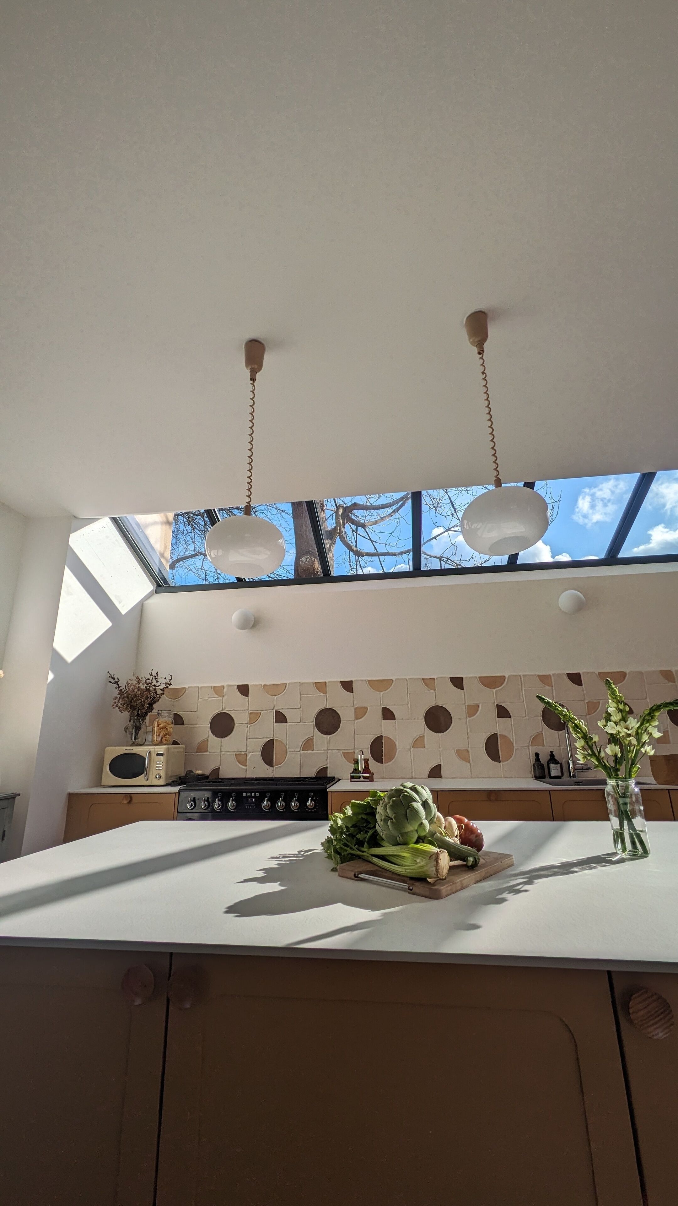 Een moderne keuken met een groot eiland, een gasfornuis en een uitzicht op de lucht door de dakramen.