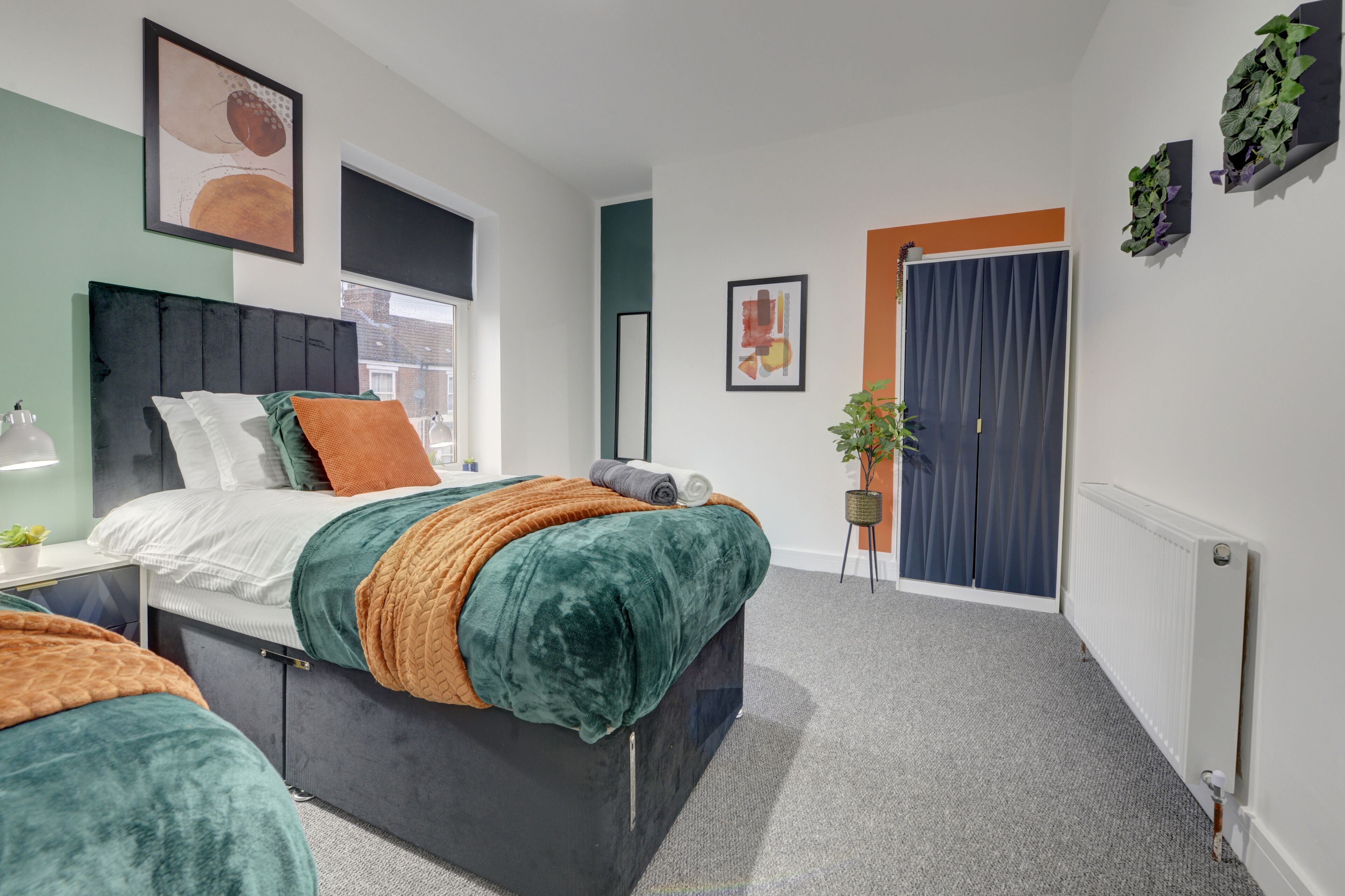 Une chambre à coucher moderne, avec un lit, des tables de chevet, une fenêtre et une porte.