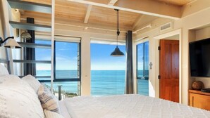 Ein Schlafzimmer mit einem großen Bett, einem Fernseher und Blick auf den Ozean.