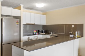 Enjoy cooking in this well-lit kitchen with a sleek refrigerator, stove, and ample counter space.