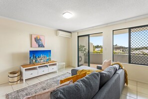 Relax in this stylish living room with a sofa and entertainment unit, offering a view of the city from the balcony.
