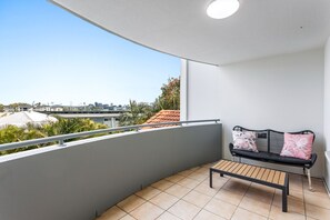 Enjoy the city view from this balcony with a comfortable bench and tile flooring.