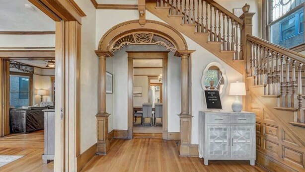 A grand staircase with ornate railings and a white console table with a sign.